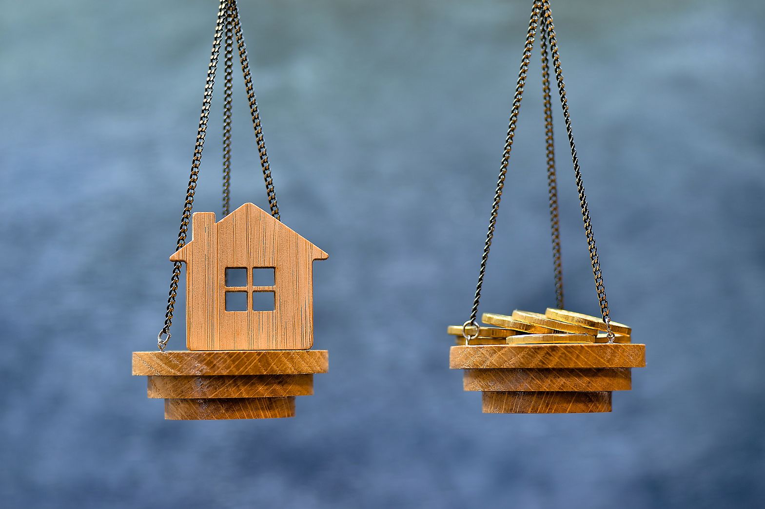 A balancing scale with house and money weighed against each other